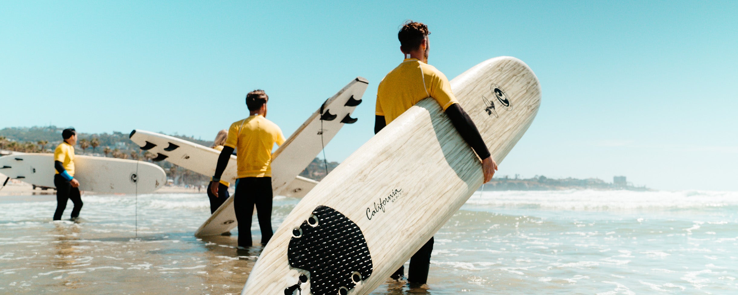 Rentals - Everyday California Surfboard Rentals. Cute surfer girl paddling on a long board in San DIego, California