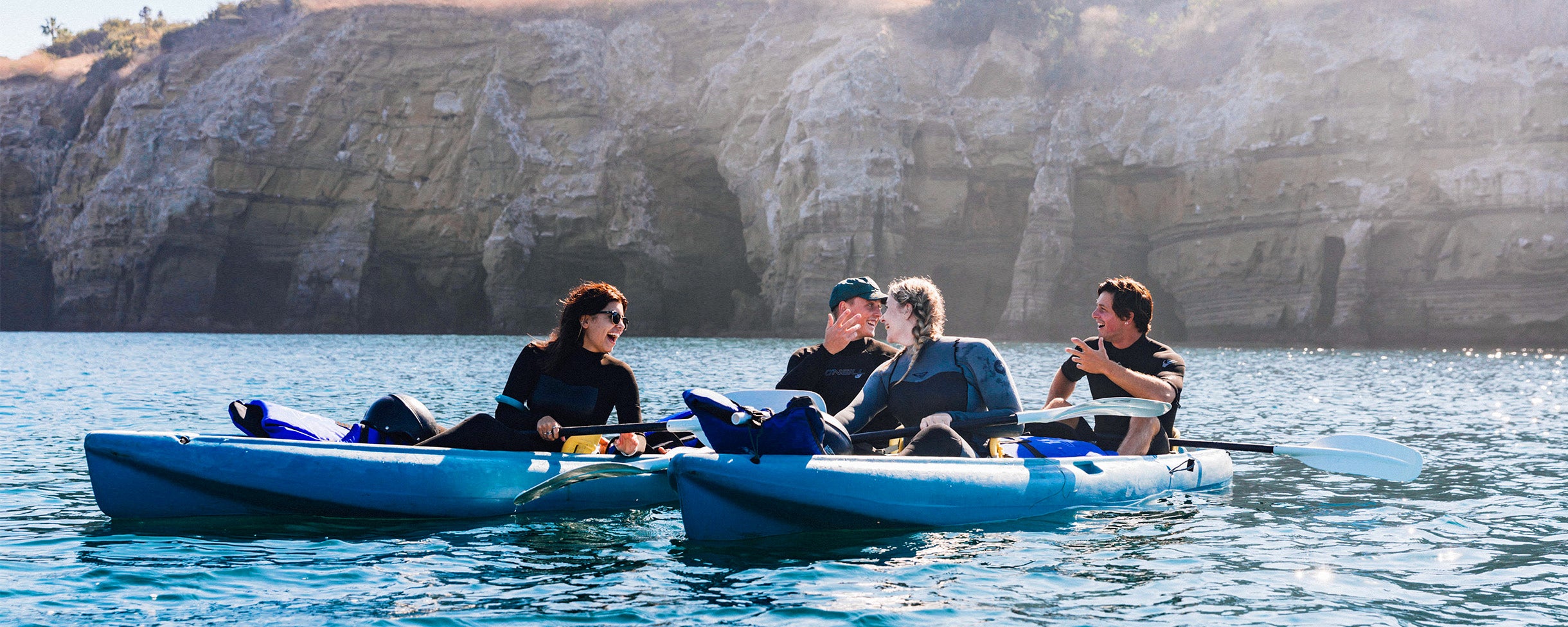A group of 4 kayakers laughing and enjoying their Sea Cave Kayak Tour in La Jolla with Everyday California.